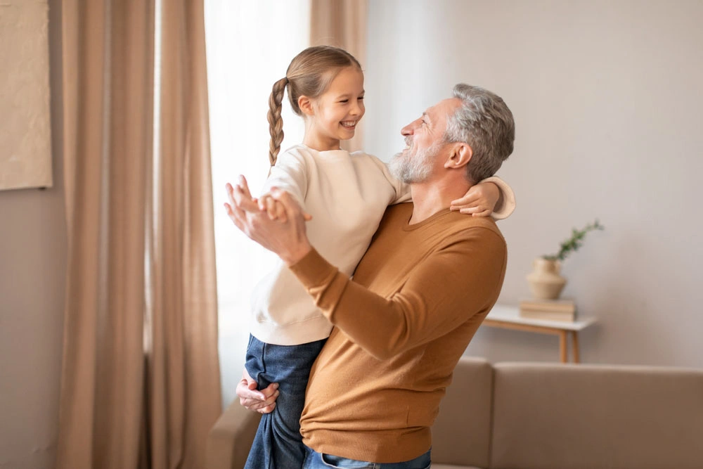 Father and daughter smiling and dancing together at home